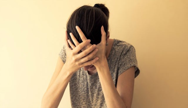 A mother of an autistic child in distress holding her hands on her forehead