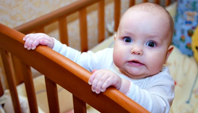 Baby standing on her bed 