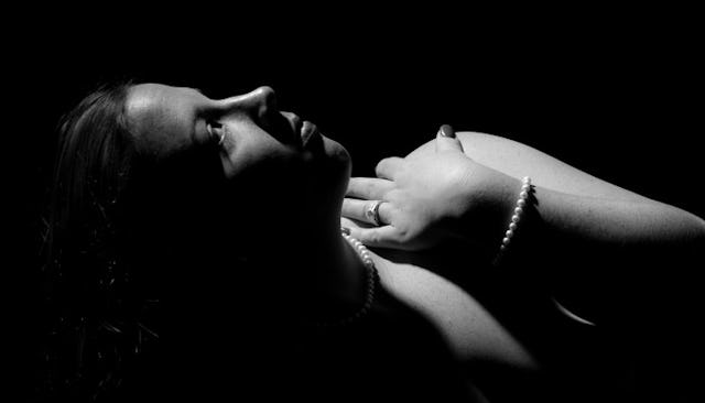 A black and white highly contrasted photo of a naked woman