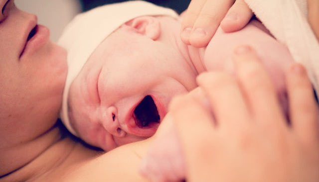 A mother holding her crying newborn on her chest