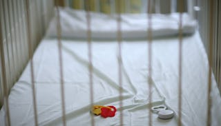 Empty baby's crib covered with a white sheet