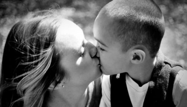 A mother kissing her son in black and white
