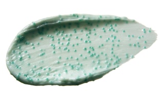 Pale green face scrub with microbead in it smeared on a white surface