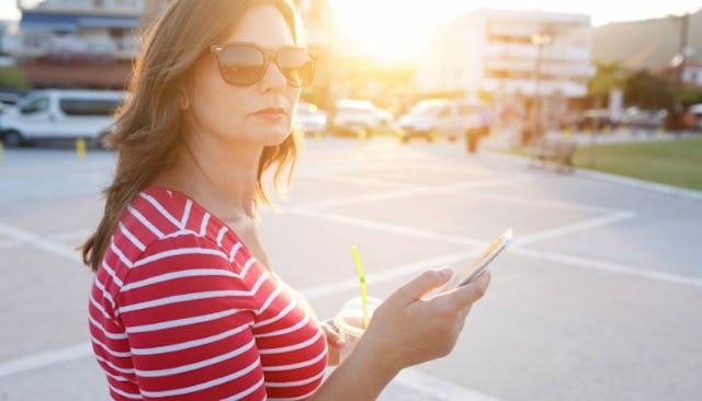 Brunette single mom in a parking field during sunset wearing a red shirt with thin white stripes and...