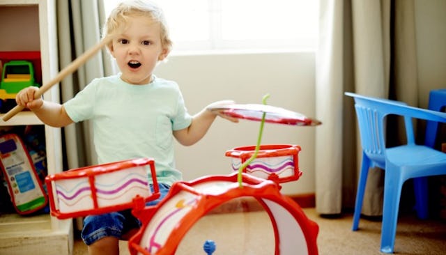 A little boy playing colorful drums in his room