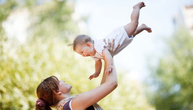 Mother holding her baby in the air in the nature during a sunny day