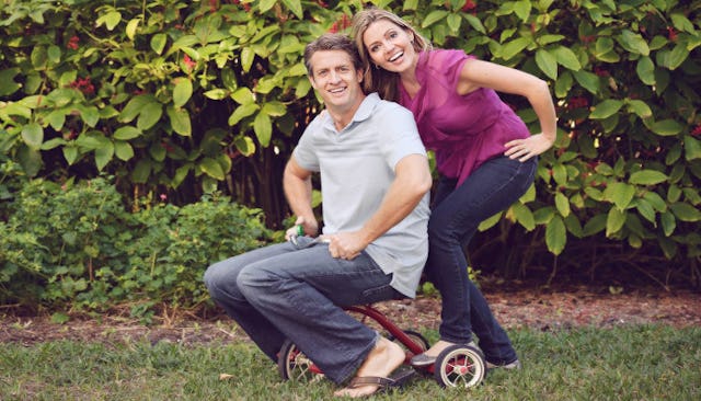 The dad sitting on a child's bicycle and the mom posing next to him in the new Holderness family vid...