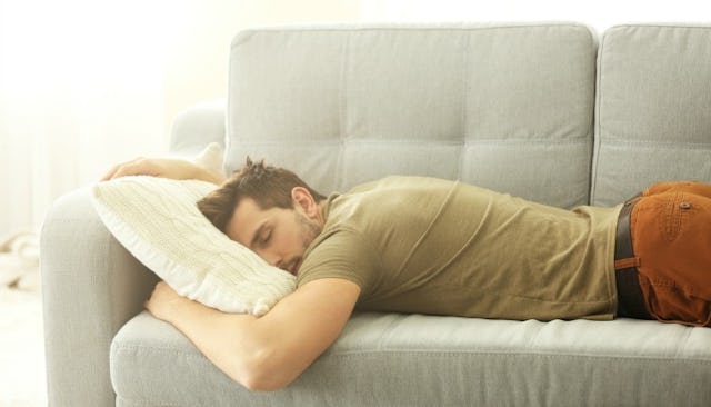 A man sleeping on his stomach on the couch after he stopped sharing a bed with his wife