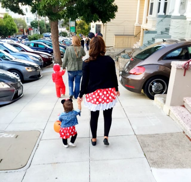 A mother and daughter wearing matching Minnie Mouse-inspired outfits while walking down a street.