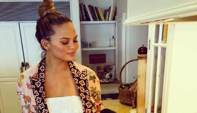 Chrissy Teigen wearing a pink kimono over a white tube top exposing her flat belly after giving birt...
