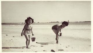 A mother and daughter playing with sand on a beach