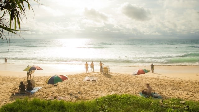 Sunny sand beach with a few people sunbathing and standing during daytime