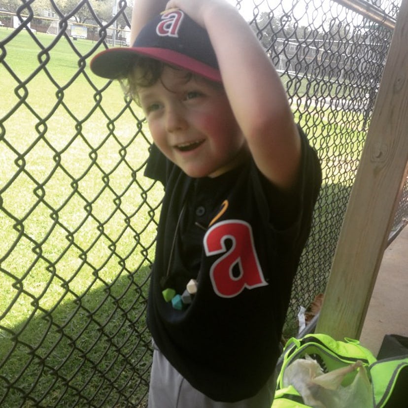 A little boy in a black T-shirt with sensory processing disorder and a black hat is standing next to...