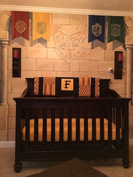 A Hogwarts inspired crib with the banners of all four houses above it on a wall