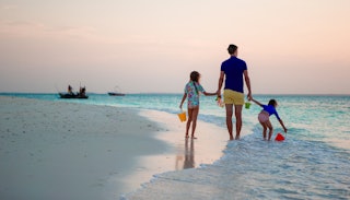 A father walking down the beach with his two daughters