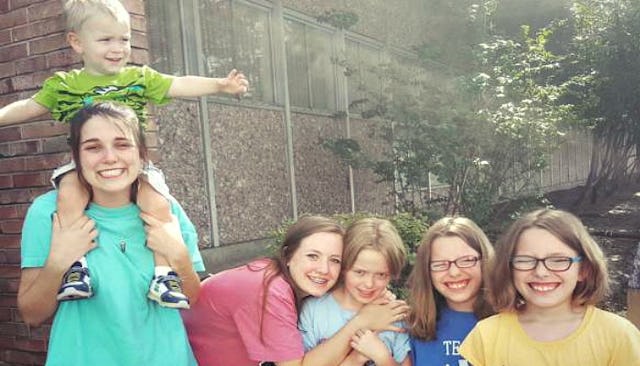 Two teenagers, three younger kids and a baby boy all from a blended family smiling.