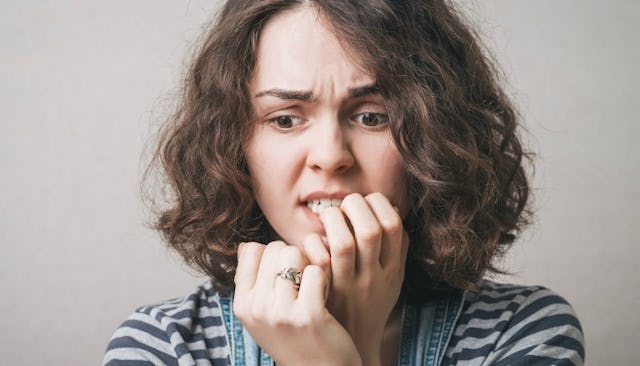A brunette woman with social anxiety biting her nails