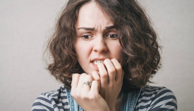 A brunette woman with social anxiety biting her nails 