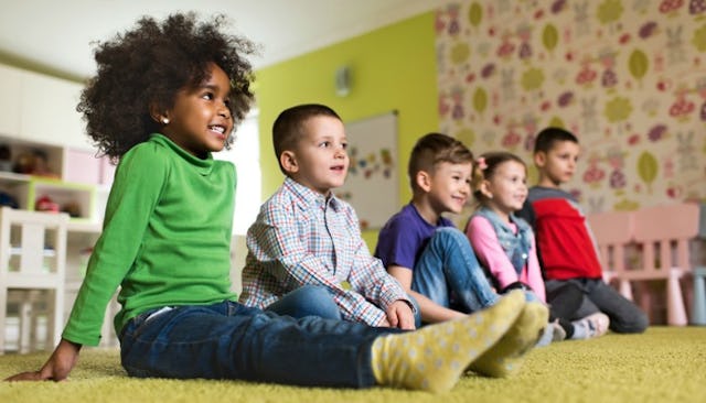 Five smiling children sitting on floor in Pre-K