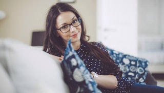 Young woman sitting on a couch while wearing glasses that make her look serious