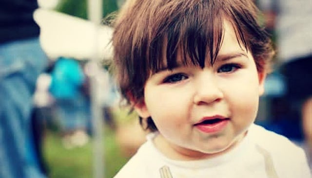 Portrait of a brunette toddler in a white shirt with a blurry background