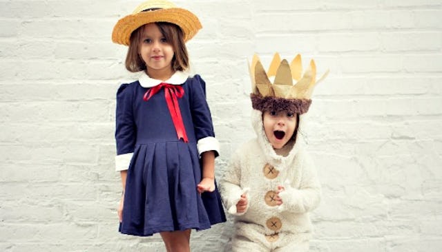 A girl in a navy dress and a small boy in a white king costume
