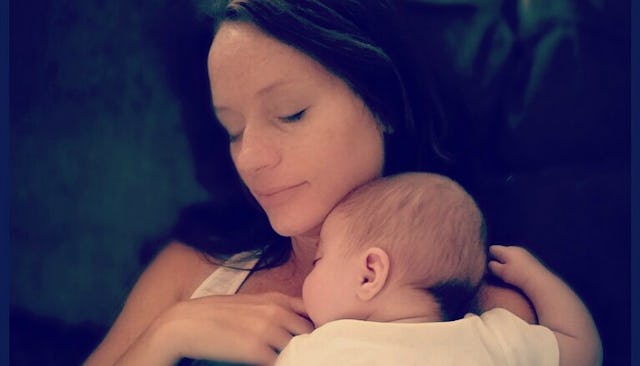 A mother holding her newborn baby on her chest while lying on a couch