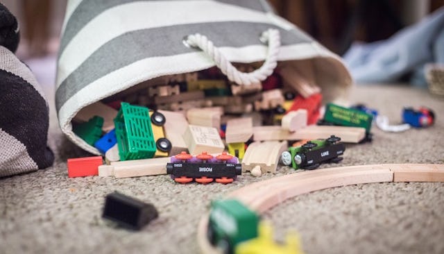 Various toddler toy cars and wooden toys in a bag on a floor