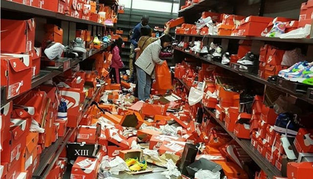 The inside of a messy Nike sneaker shop, with the shoe boxes on the floor while people are still sho...