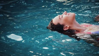 A woman on a kid-free vacation floating and relaxing in a pool