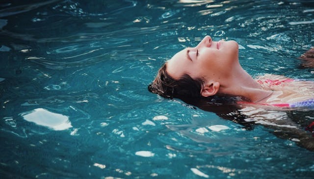 A woman on a kid-free vacation floating and relaxing in a pool