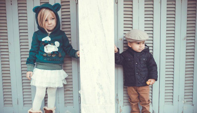 Two kids leaning on opposite sides of a wall