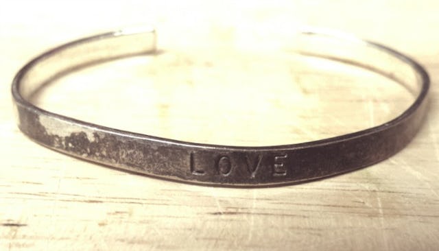 A broken and worn-out metal bracelet with the word "love" engraved