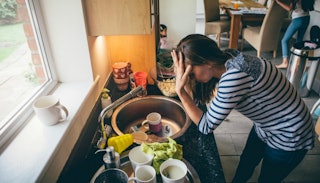 A worried woman leaning on the kitchen counter and is having a mom meltdown