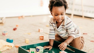 A kid in his playroom playing with letter cubes.