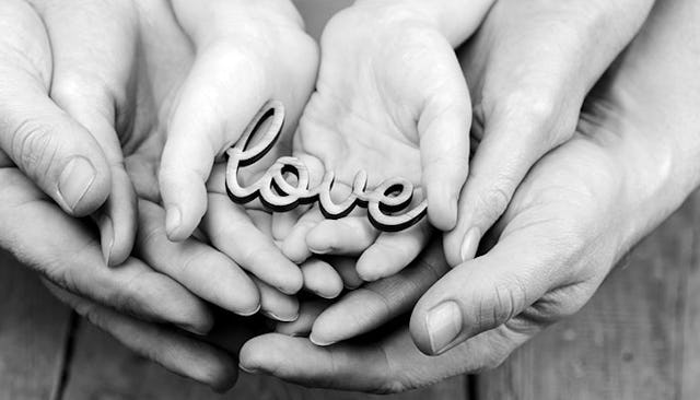 Three pairs of hands, a father holding his wife's hands, who's holding their child's hands