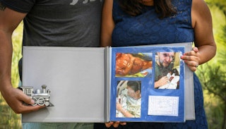 A mother and father holding a photo album with photographs of their stillborn son