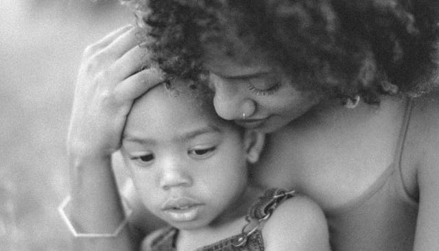 A woman hugging her child that has a worried facial expression