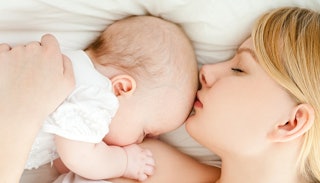 Mom and her newborn baby breastsleeping in bed