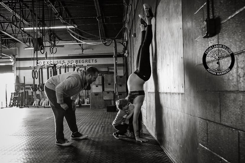 Photograph from a maternity shoot of a fit mom doing a hand stand while her child is kissing her