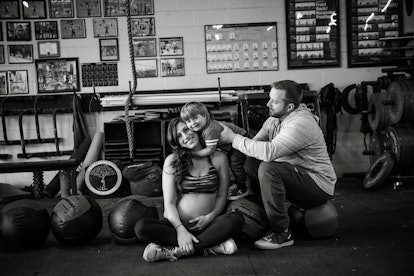 Photograph from a maternity shoot of a fit mom smiling with her husband and child