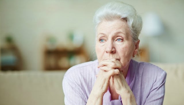 A concerned cut out mom sitting with her face leaning on her crossed hands