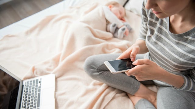 A mother who is always on her phone typing a message next to her sleeping baby