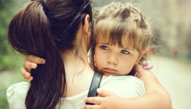 A light brown-haired toddler girl with big blue eyes, holding onto her mother, hugging her