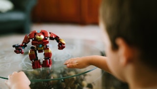 A boy looking at his red Transformer toy that is placed on a glass table