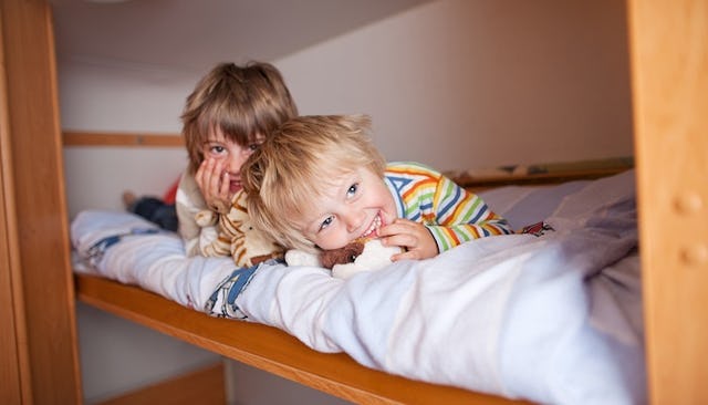 Two young kids who share a room lying on the bed together