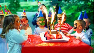 A lot of kids next to a cake at an outdoor birthday party