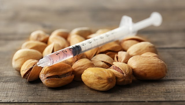 An syringe on a pile of pistachios representing food allergies