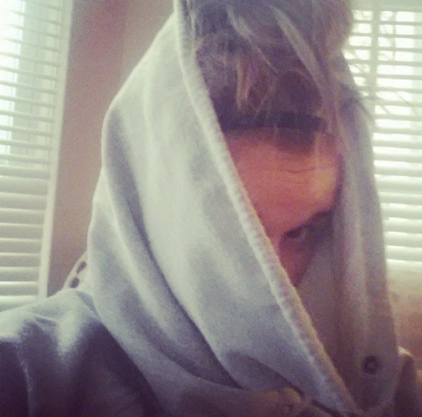 A woman covering her face with a hoodie