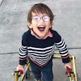 Rachelle Chase's son in a striped sweater and glasses with a device helping him walk